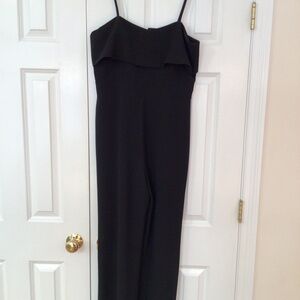 Black WAYF jumpsuit with spaghetti straps and draped top.